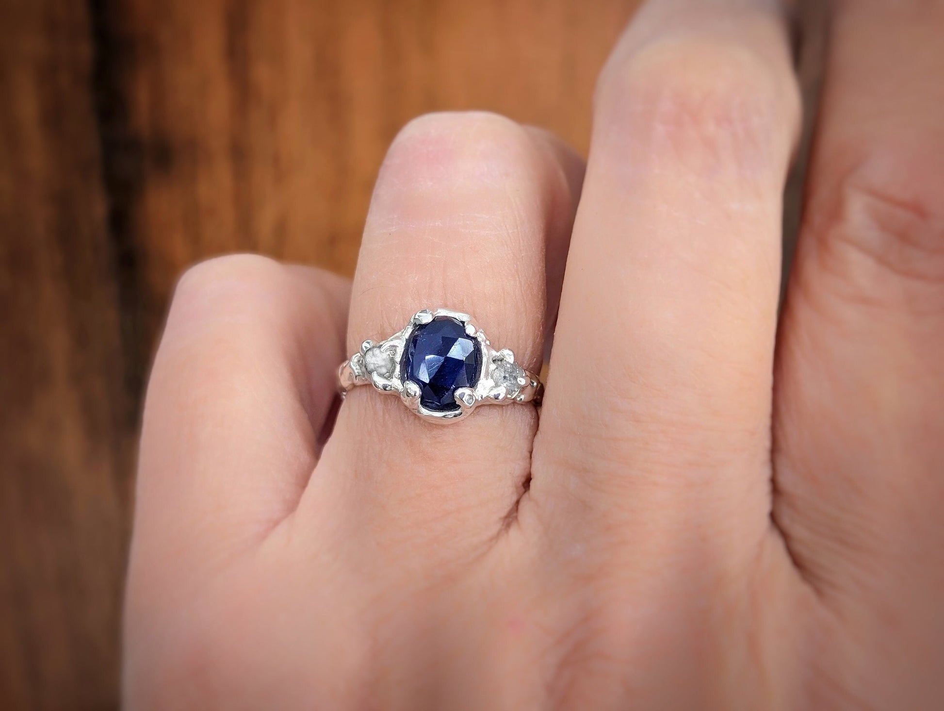 Blue sapphire and diamond engagement ring on hand, showcasing unique design and timeless elegance.