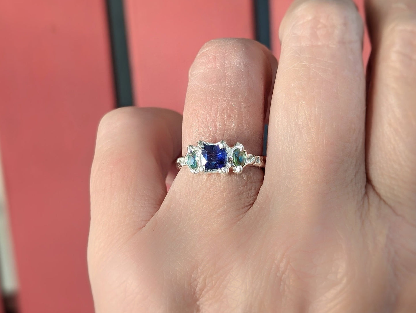 Handcrafted Blue Sapphire and Tourmaline engagement ring in 14k Gold, showcasing elegant rustic design on model's hand.