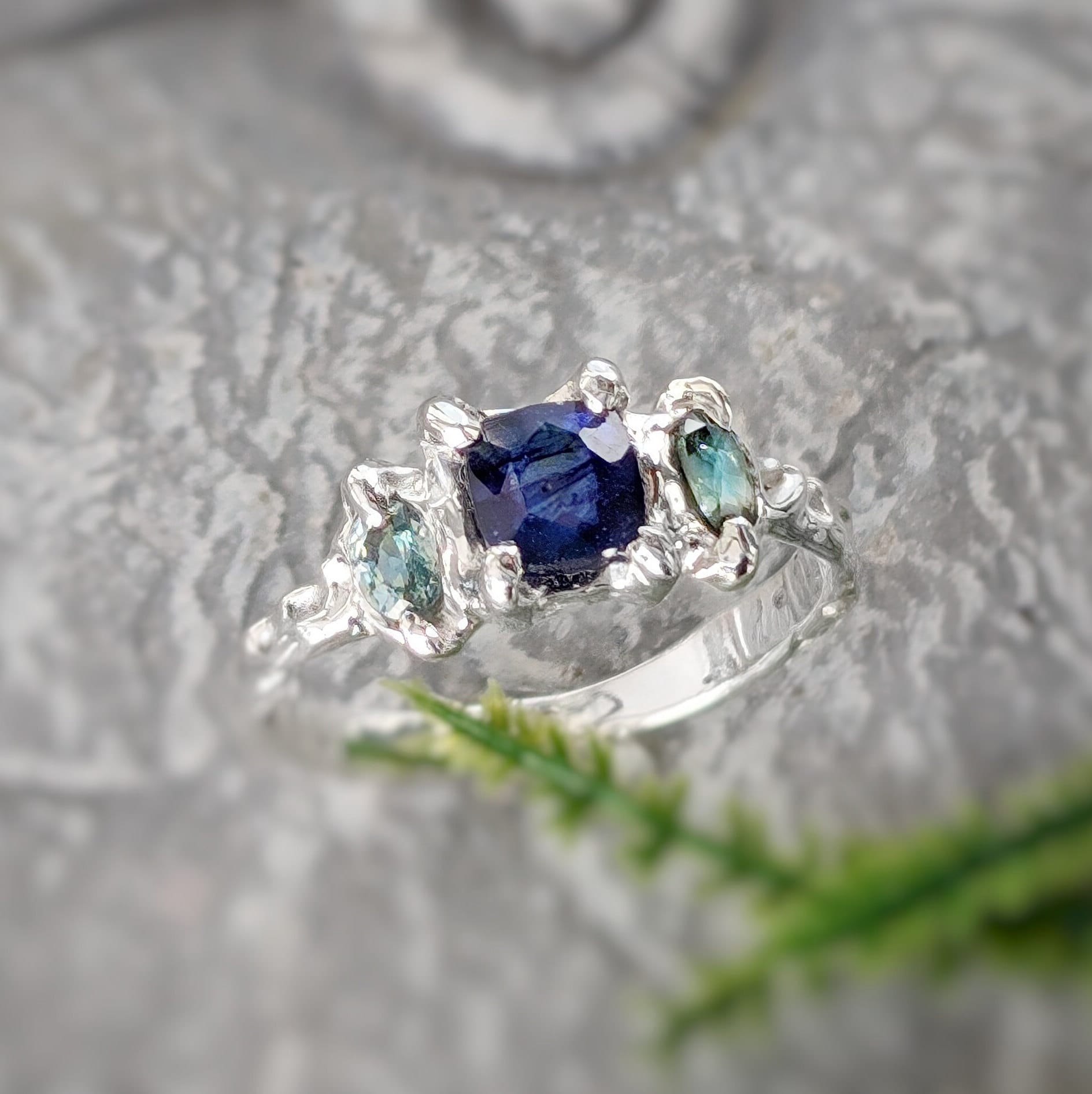Elegant Blue Sapphire and Tourmaline engagement ring in textured Solid Sterling Silver, featuring a square blue sapphire and teal tourmalines.