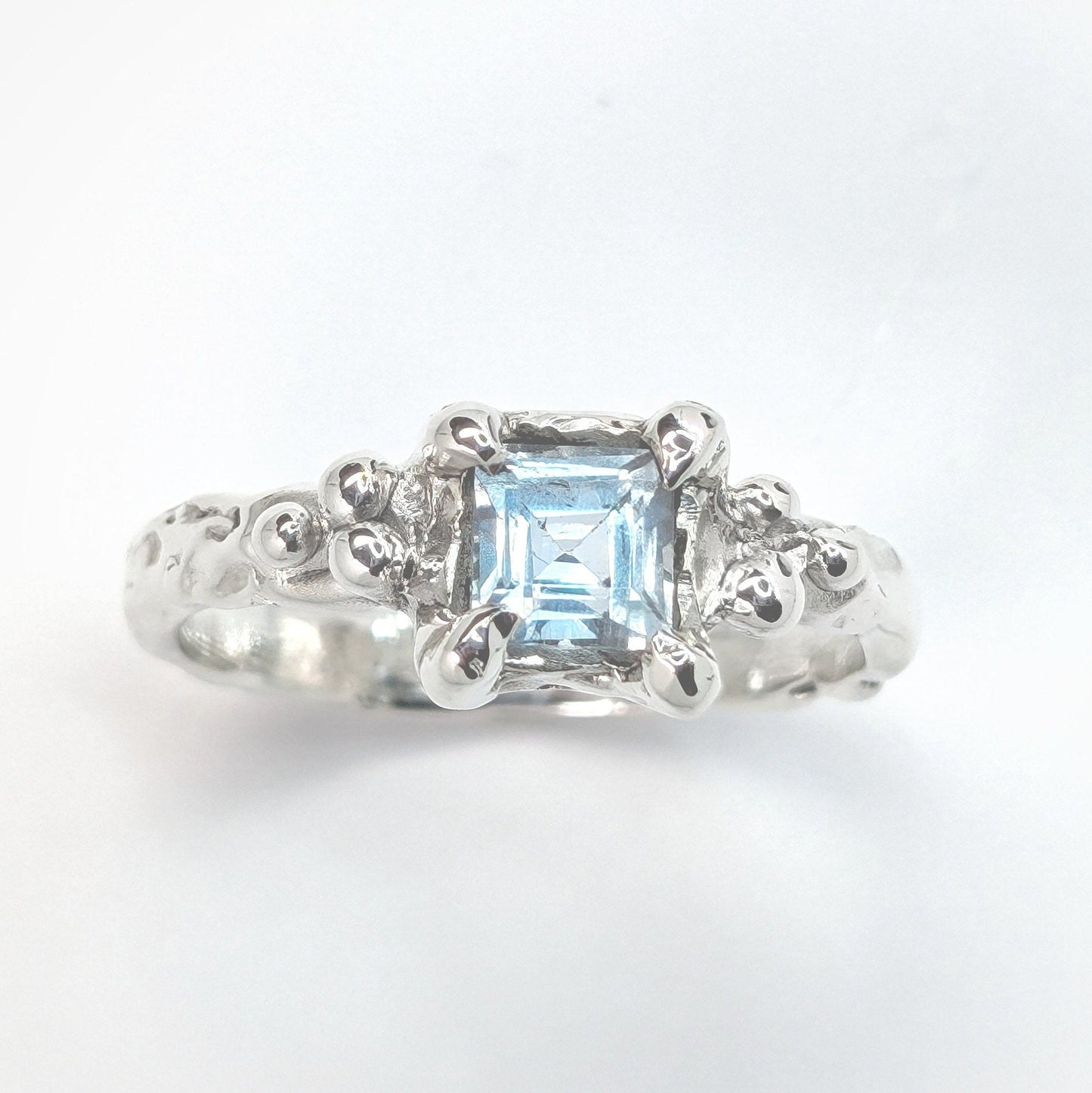 Handcrafted blue topaz engagement ring in sterling silver with organic textured band.