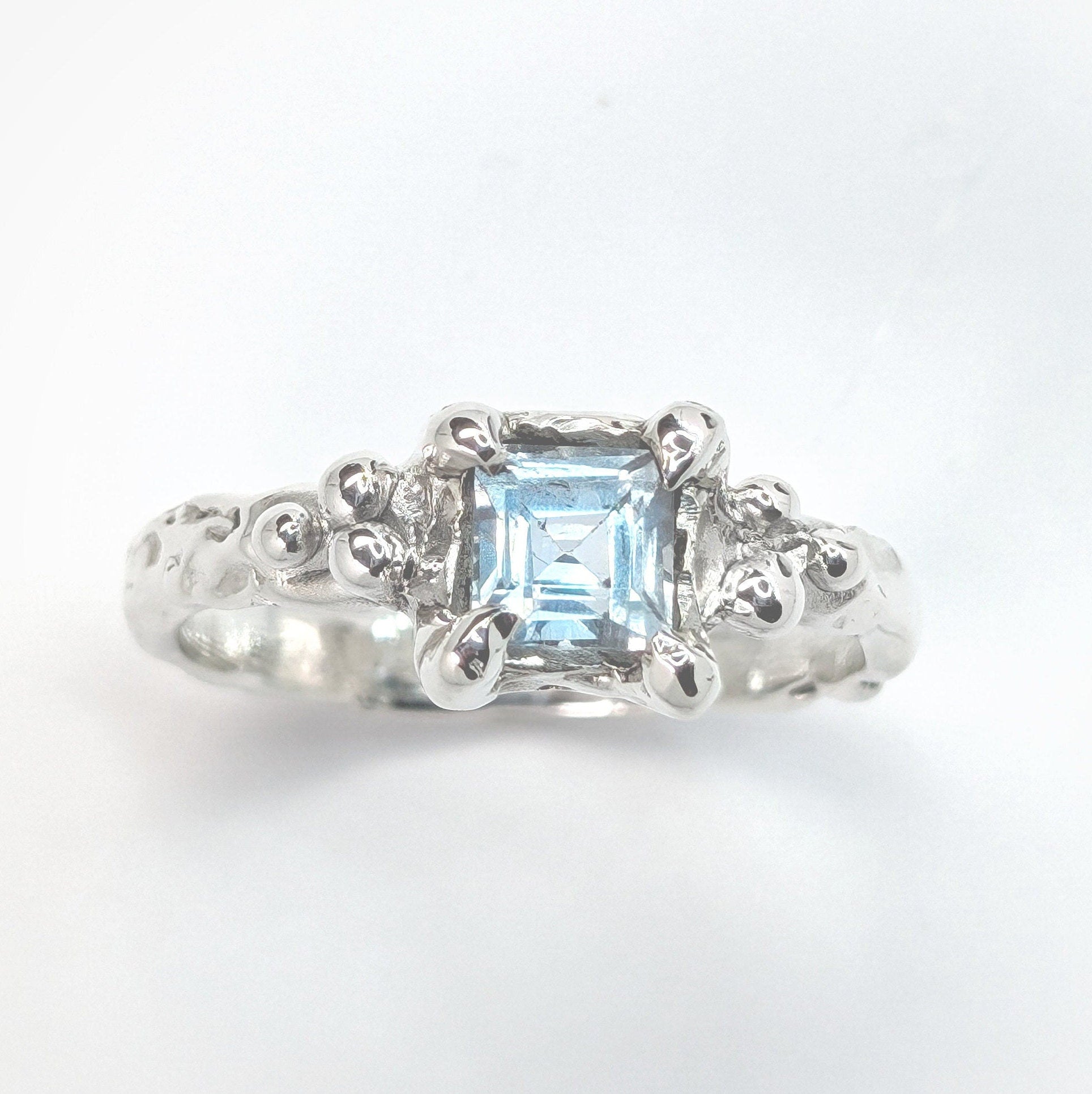 Handcrafted blue topaz engagement ring in sterling silver with organic textured band.