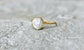 Small freshwater Keshi pearl ring on a textured surface, featuring a solid 14k gold band and a luminous pearl.