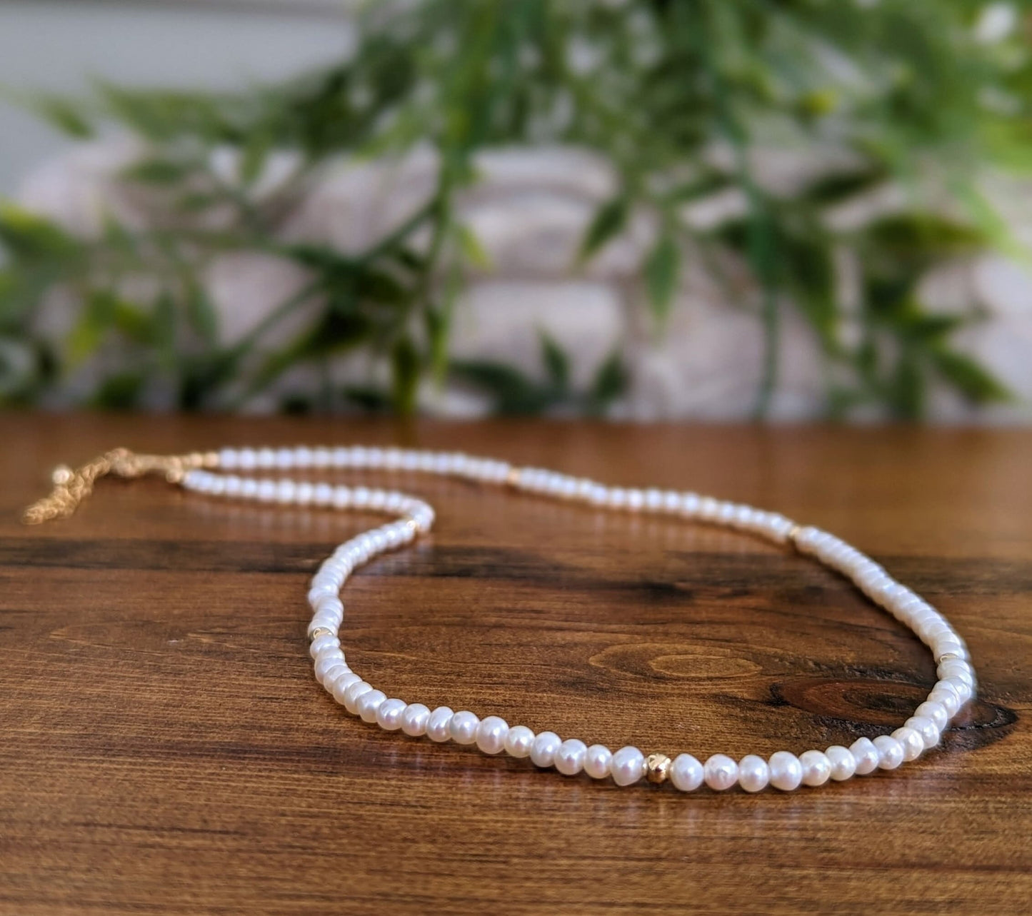 Delicate freshwater pearl necklace on wooden surface, showcasing elegance and timeless beauty for special occasions.