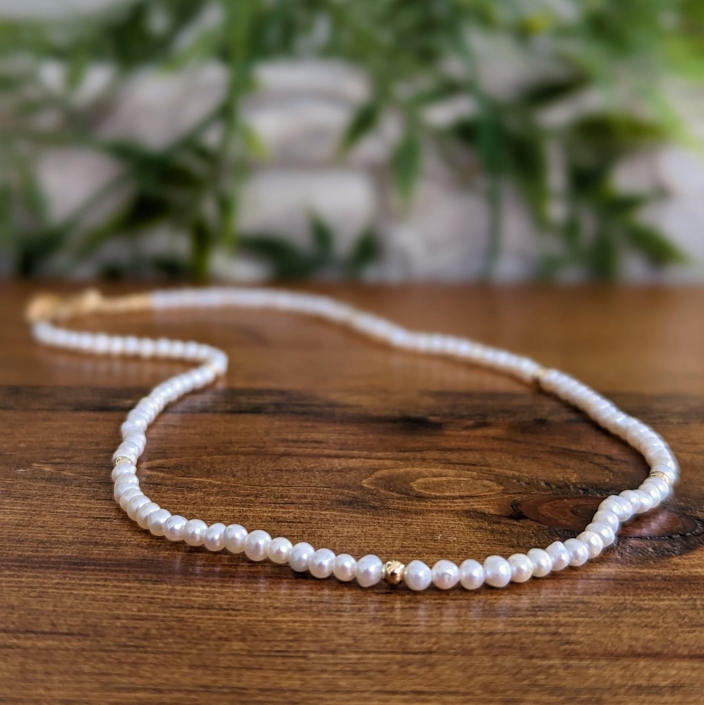 Handmade freshwater pearl necklace on wooden surface, ideal for brides and Mother's Day gifts.