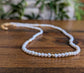 Delicate freshwater pearl necklace with gold accents on wooden background, perfect for weddings and as a Mother's Day gift.