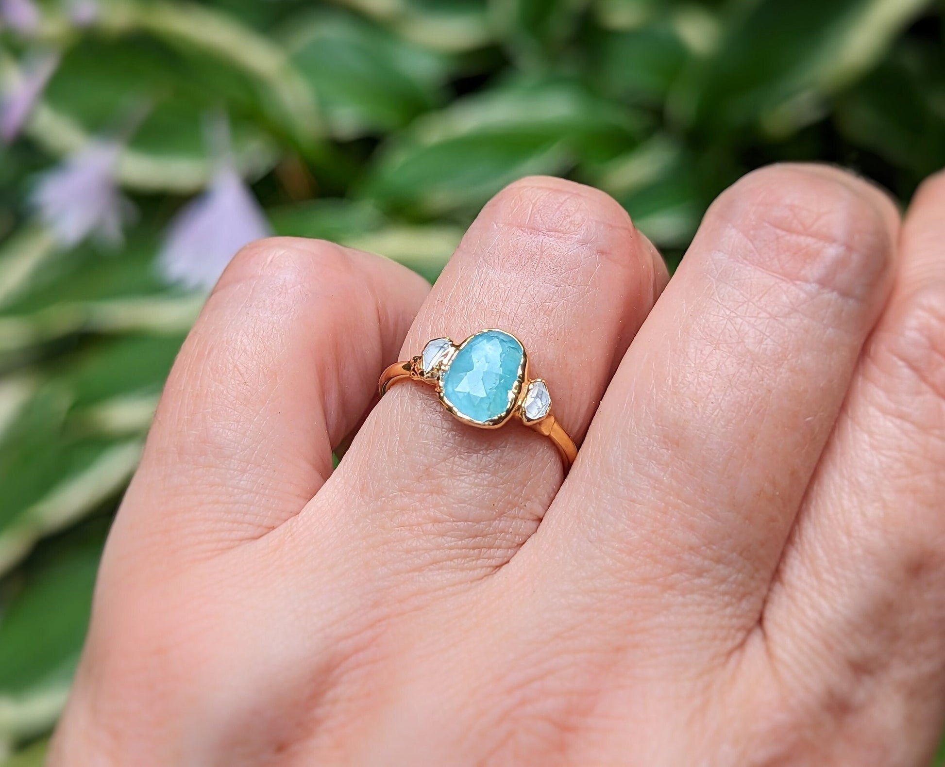 Aqua blue Grandidierite and diamond ring in 18k gold on a hand, showcasing its unique beauty and craftsmanship.