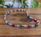 Handcrafted multi tourmaline bead necklace featuring stunning rainbow colors on a wooden background.