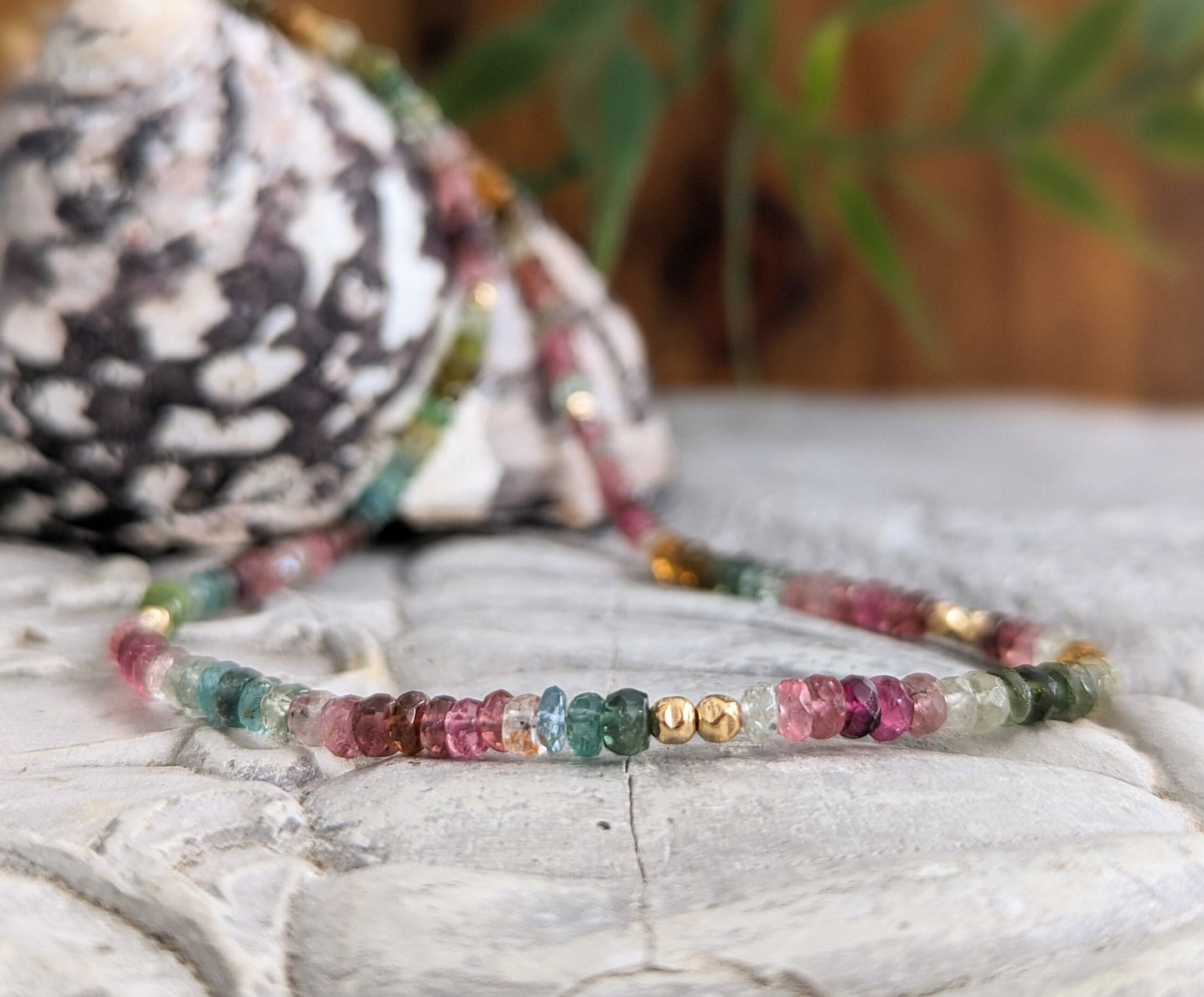 Handcrafted Multi Tourmaline bead necklace featuring vibrant colors and gold accents on a natural background.