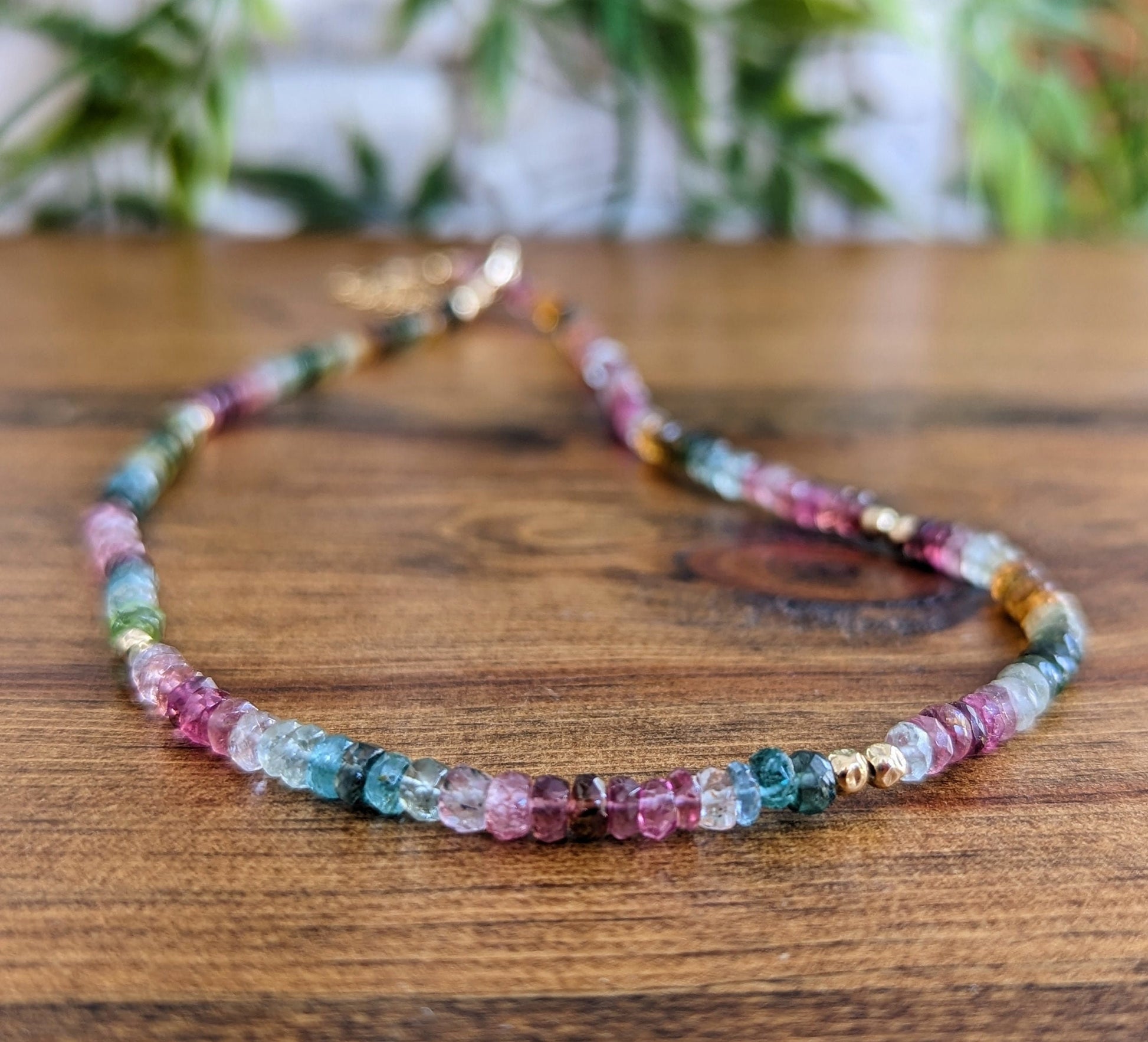 Handcrafted Multi Tourmaline bead necklace featuring vibrant colors on a wooden surface.