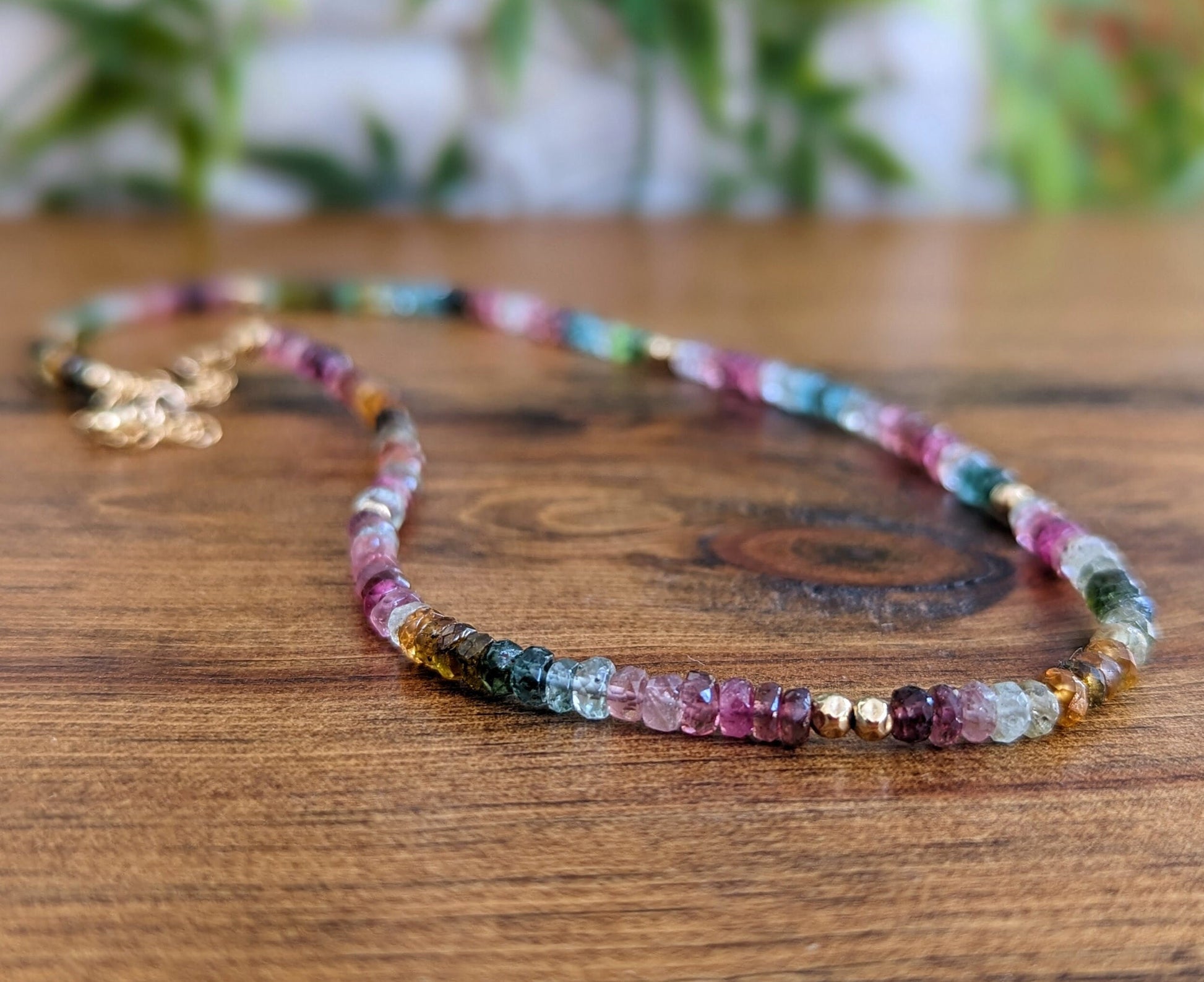 Handcrafted Multi Tourmaline bead necklace featuring vibrant colors and unique hues on a wooden background.
