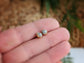 Raw diamond stud earrings in gold settings held in a hand, showcasing their natural, uncut beauty.