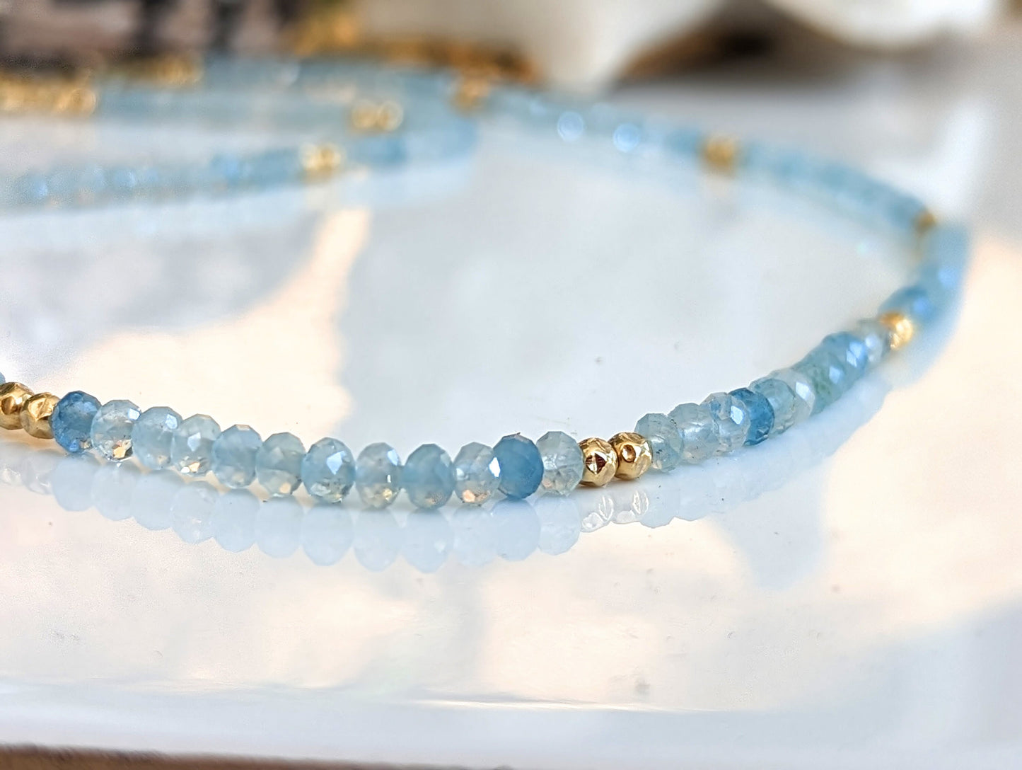 Handmade aquamarine bead necklace featuring soft blue gemstones and gold accents, symbolizing calmness and loyalty.