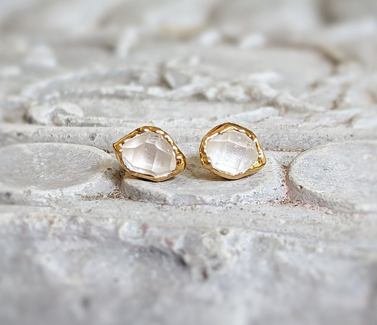 Herkimer diamond stud earrings with golden setting on textured surface, perfect for bridal or everyday elegance.