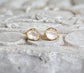 Herkimer diamond stud earrings with golden setting on textured surface, perfect for bridal or everyday elegance.