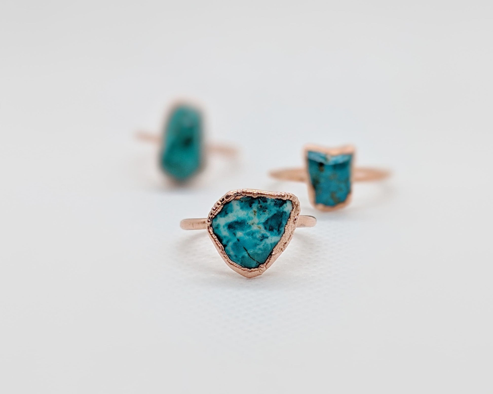 Natural turquoise rings with unique shapes and rose gold settings, showcasing vibrant aqua-blue hues.