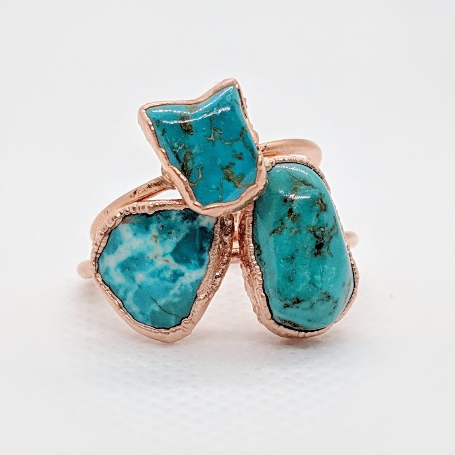 Natural turquoise ring with three unique stones set in rose gold, symbolizing calm energy and throat chakra connection.