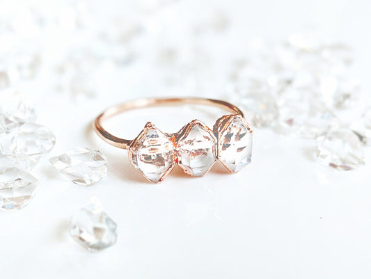 Handcrafted triple Herkimer diamond ring on a gold band, surrounded by sparkling quartz crystals.