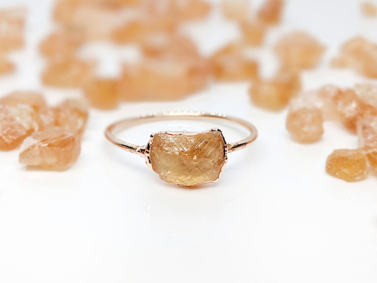 Raw Hessonite Garnet ring on a delicate band, surrounded by golden crystals, evoking a warm summer day.