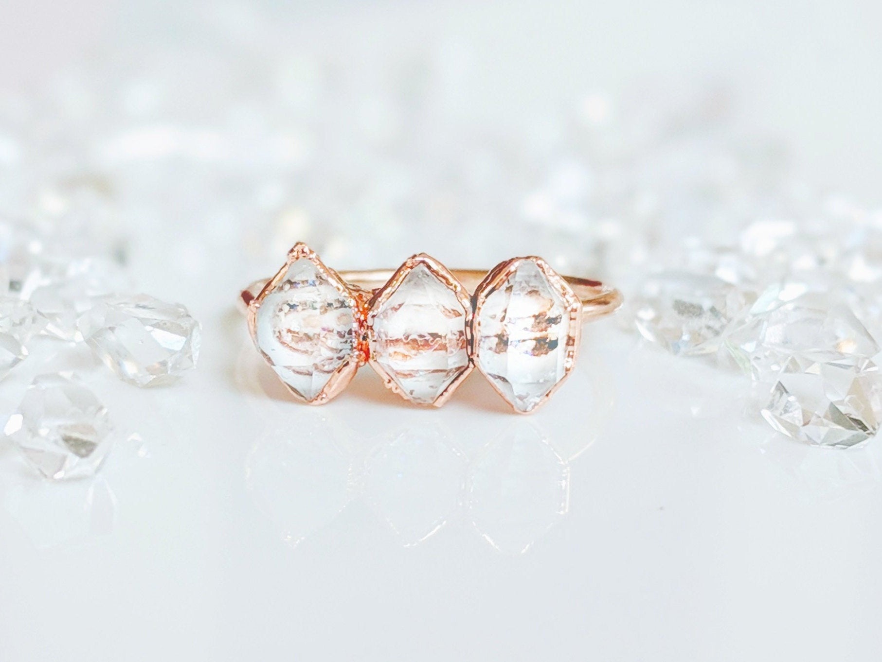 Handcrafted triple Herkimer diamond ring on a reflective surface with scattered crystals, perfect for everlasting love.