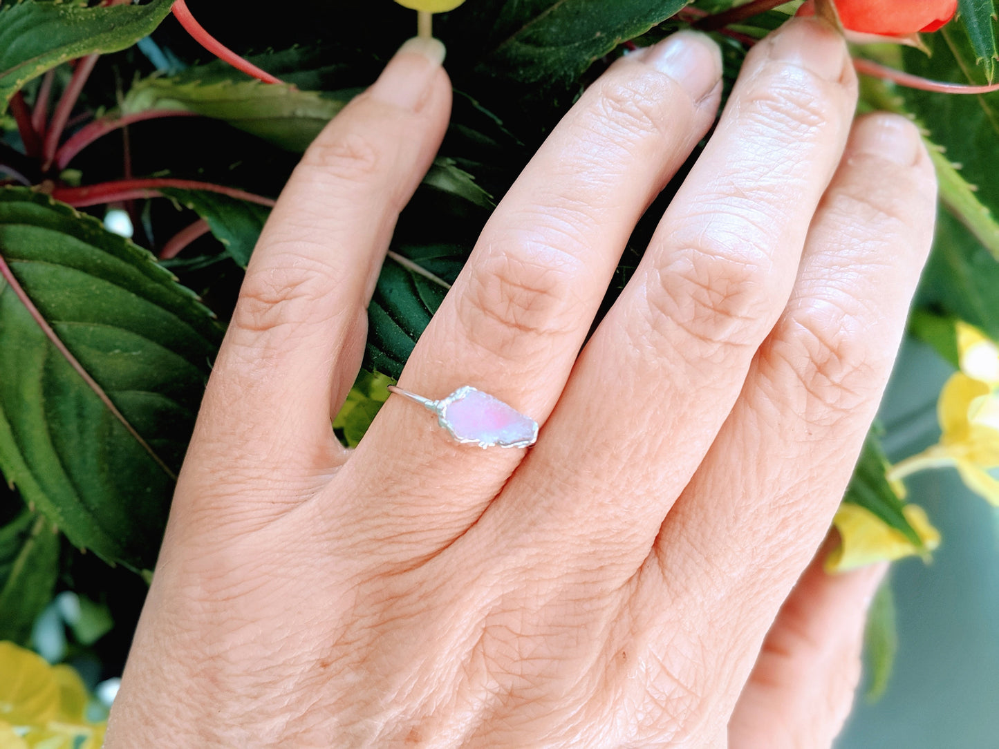 Hand wearing a raw pink Morganite ring on a Sterling Silver band with floral background.