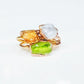 Handmade stackable rings featuring raw Imperial Topaz, white stone, and green stone on a gold band.