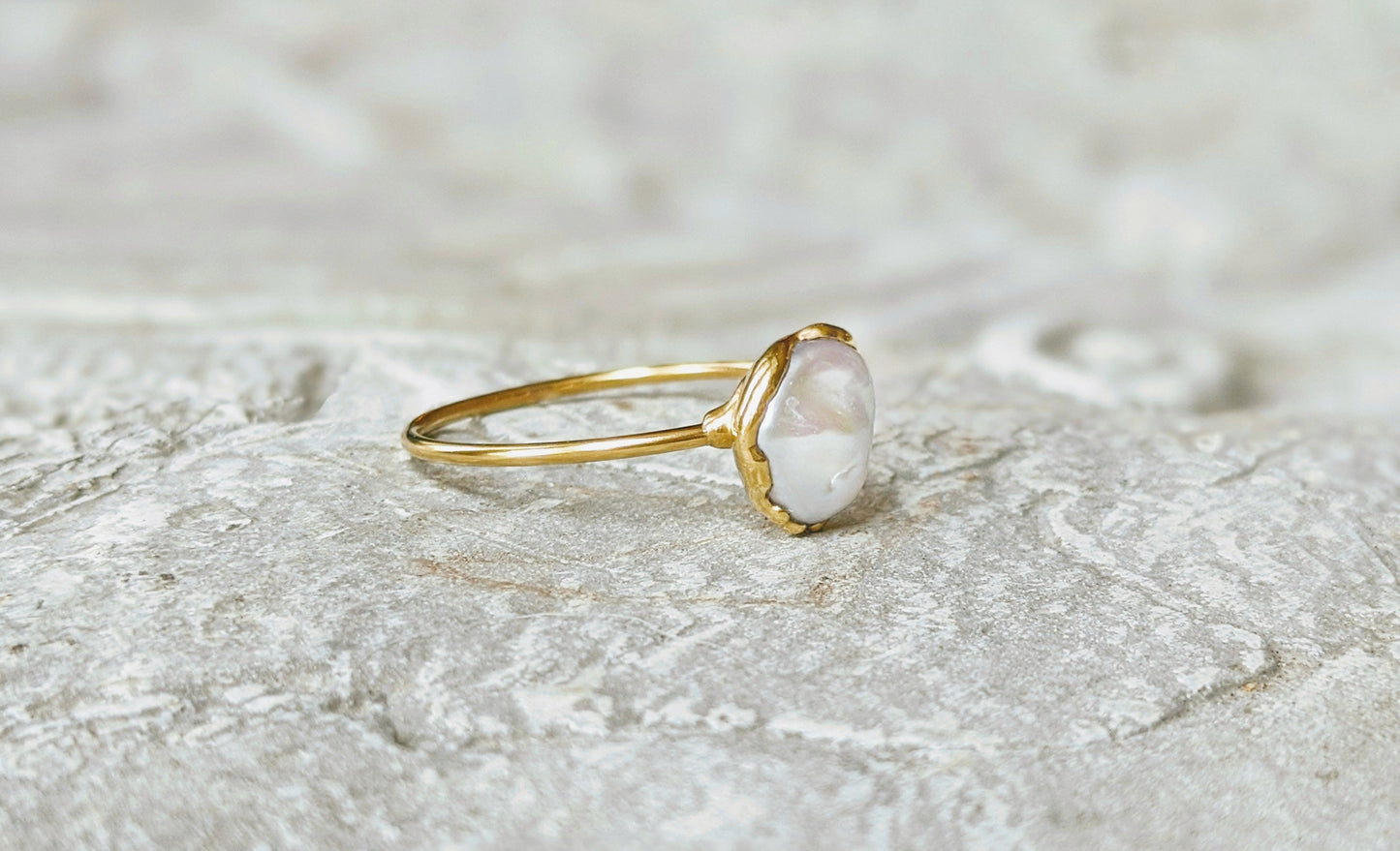 Small freshwater Keshi pearl ring on a textured surface, showcasing an 8mm pearl set in a solid 14k gold band.