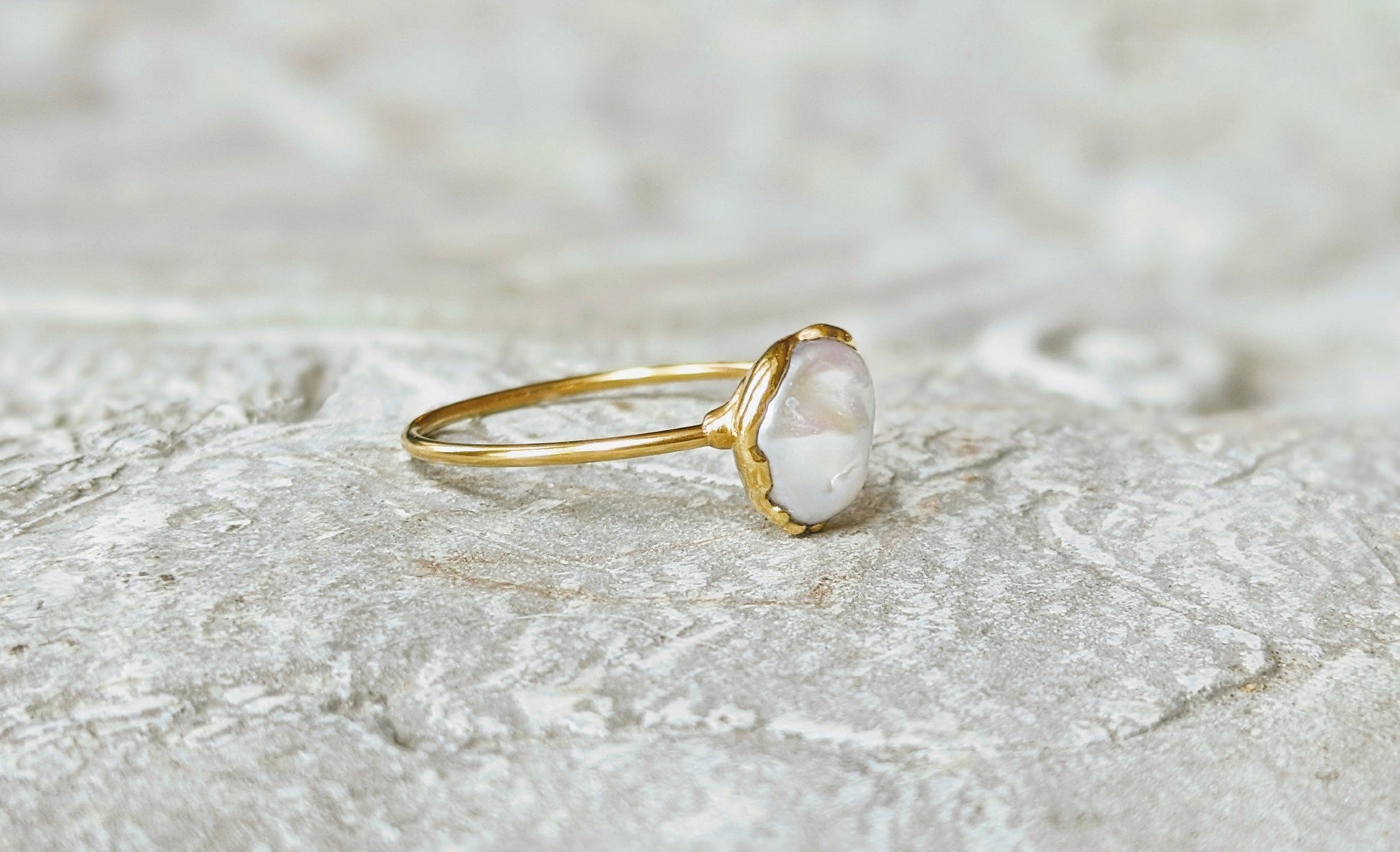 Small freshwater Keshi pearl ring on a textured surface, showcasing an 8mm pearl set in a solid 14k gold band.