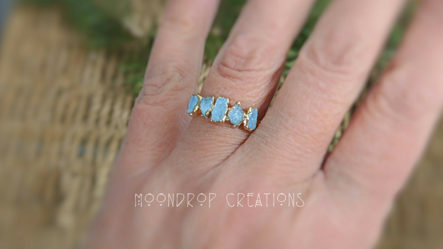 Raw aquamarine March birthstone ring on hand, featuring 5 natural stones set on a 14k gold filled band.
