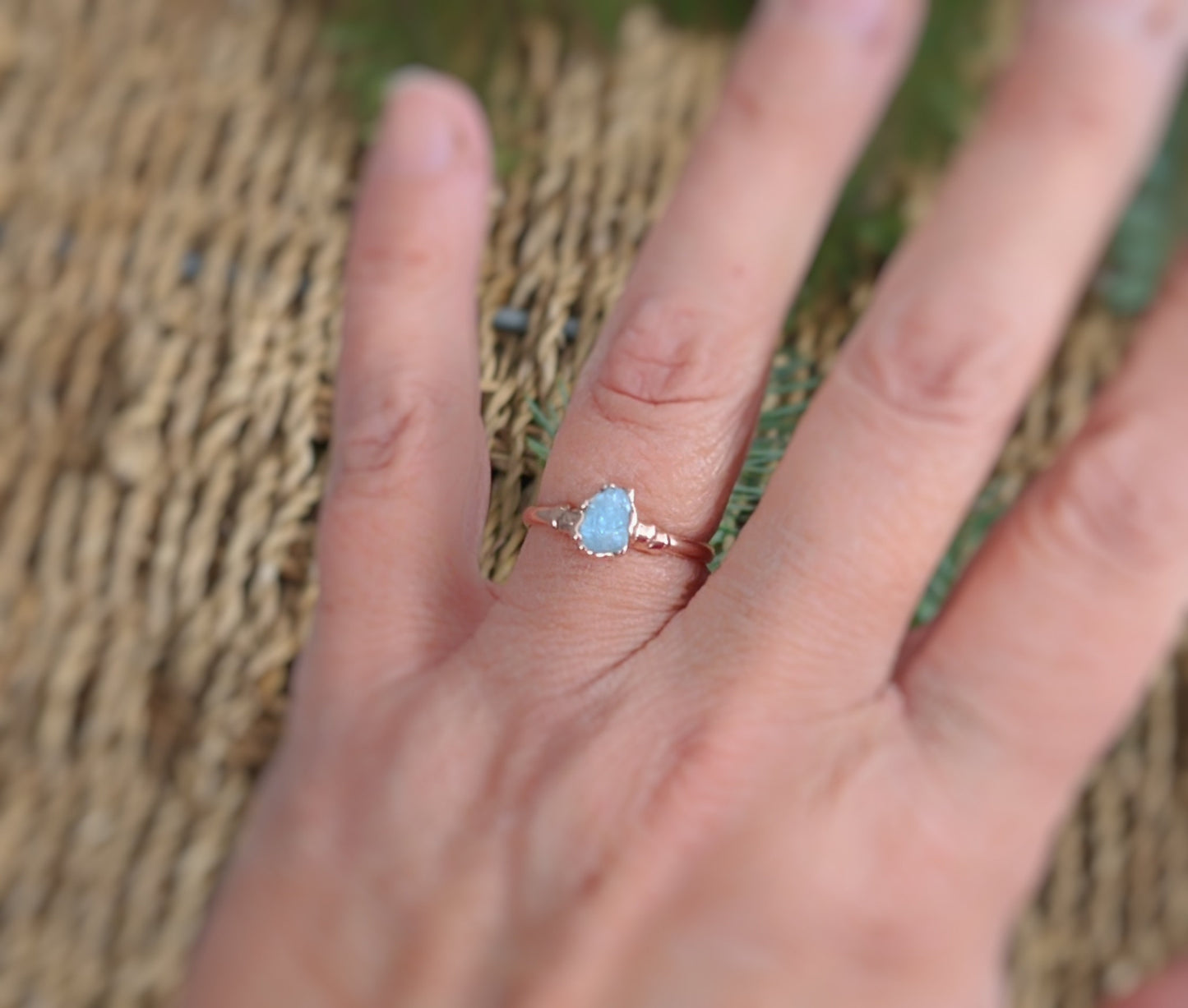 Raw Aquamarine ring on a hand, featuring a natural stone set on a 14k Gold filled band, surrounded by a natural background.