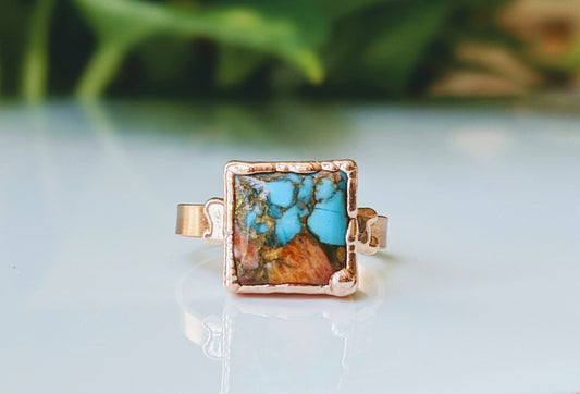 Handcrafted Spiny Oyster copper turquoise ring on a polished surface, showcasing unique gemstone details.