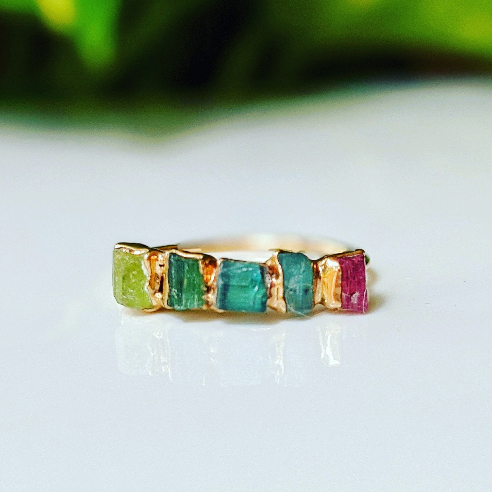 Raw Tourmaline eternity ring with multi-color stones on a gold band, perfect for any occasion.