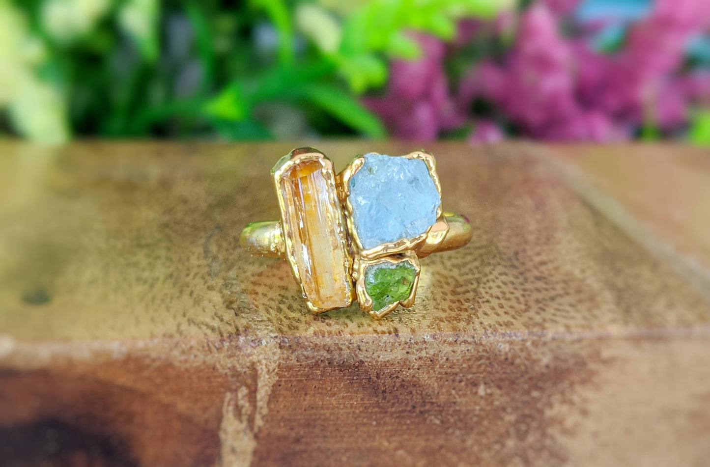 Raw topaz, aquamarine, and peridot cluster ring on gold band, perfect summer jewelry.