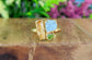 Raw topaz, aquamarine, and peridot cluster ring on gold band, perfect summer jewelry.