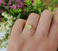 Raw yellow Apatite ring on a hand, featuring a 14k gold filled band and surrounded by flowers.