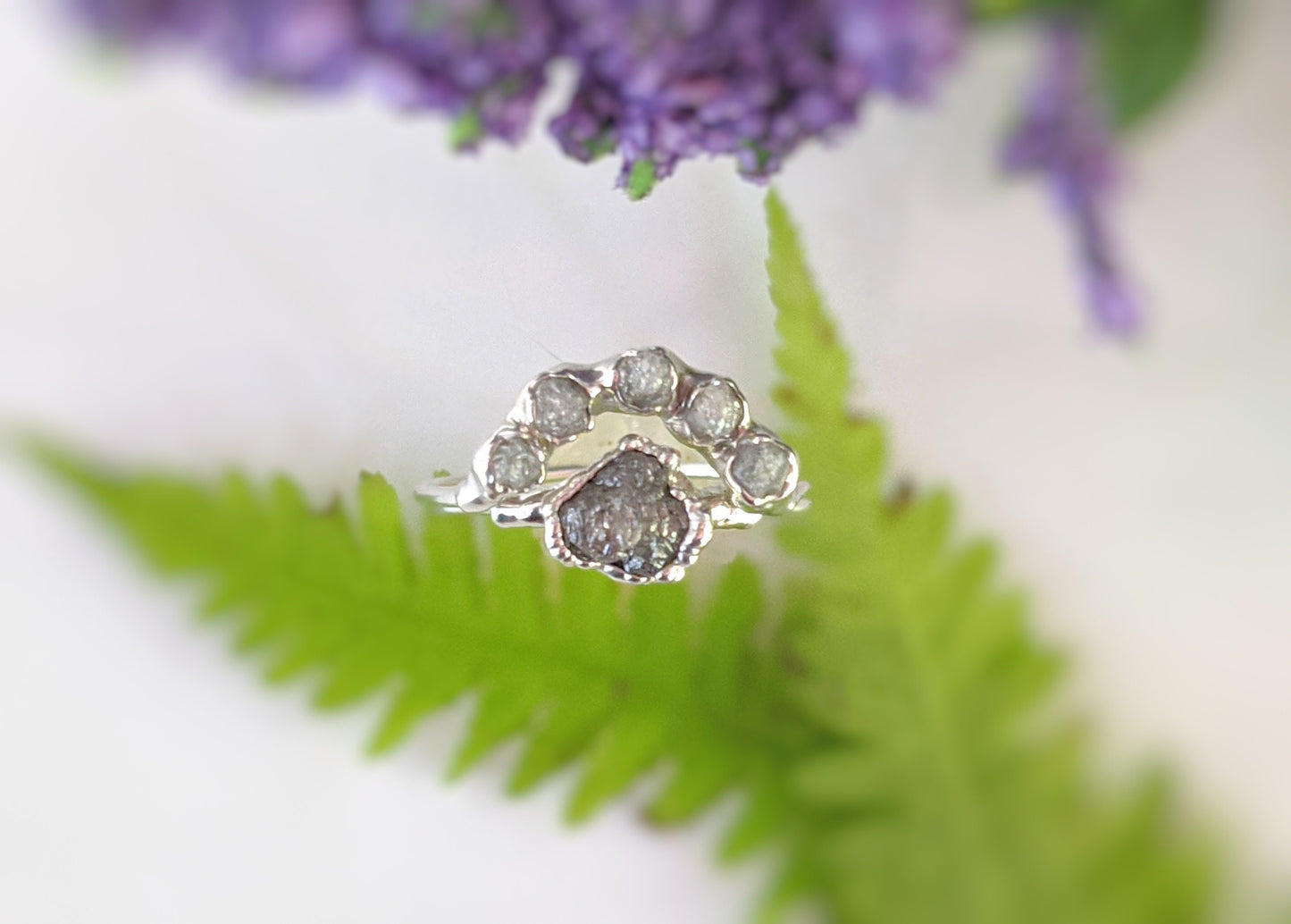 Handcrafted Raw diamond Chevron wedding ring set with silver-grey diamonds, nestled on lush greenery.