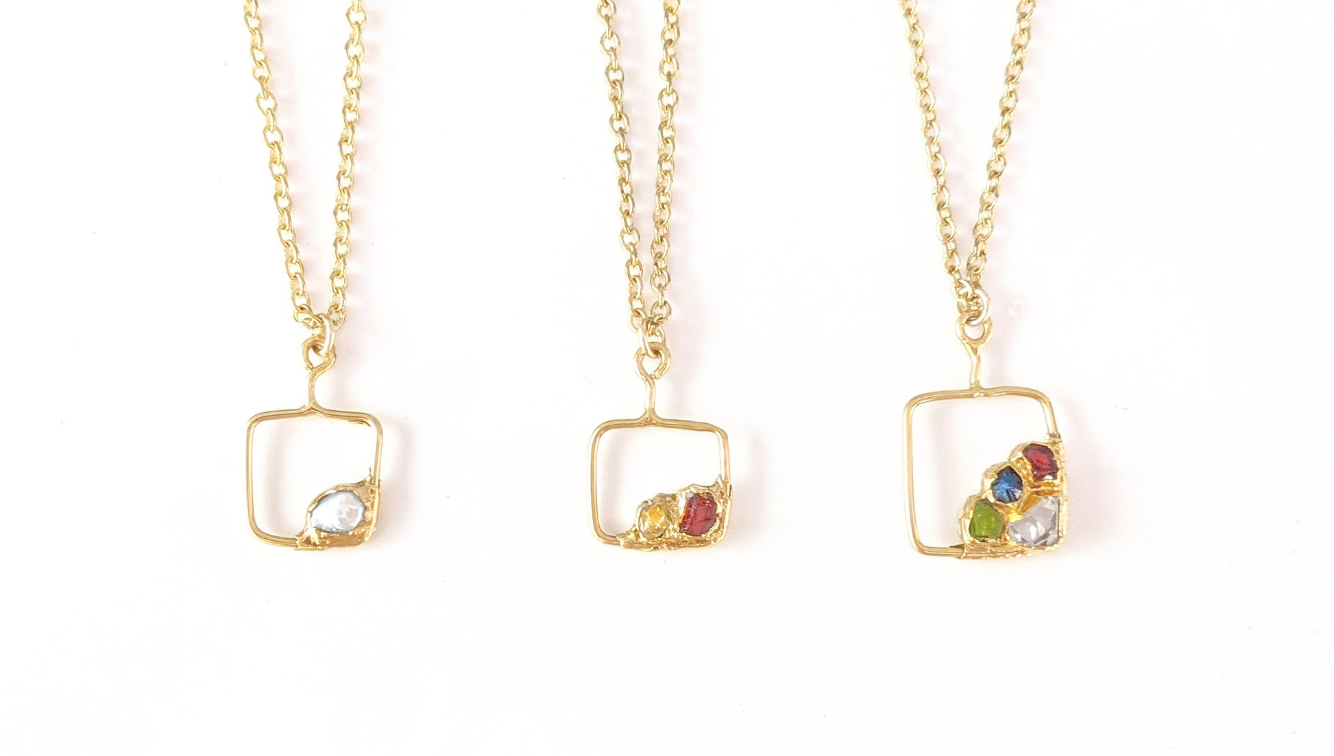 Family birthstone necklaces with square gold pendants and various raw gemstones, perfect for mothers.