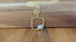 14k gold filled square pendant necklace with raw gemstone on wood background.