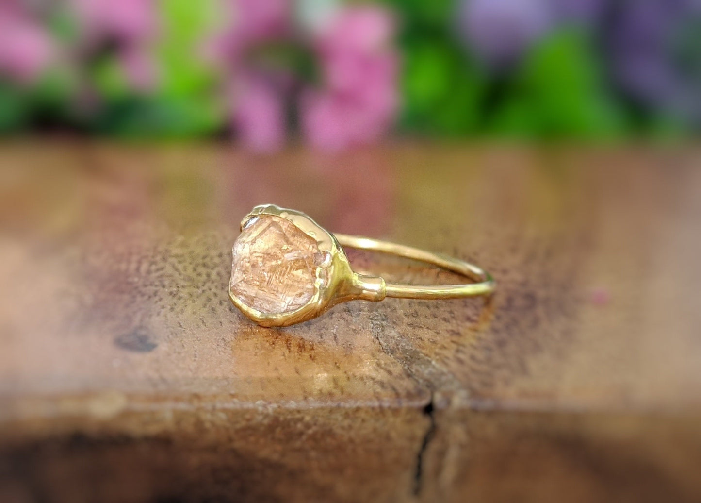Raw Hessonite Garnet ring on a wooden surface, featuring an 18k Gold plated band and a unique golden gemstone.