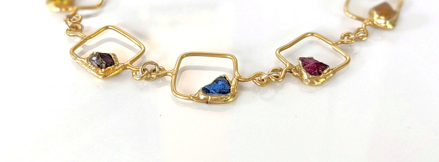 Personalized family birthstone necklace featuring colorful raw gemstones in gold square links.