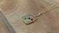Personalized family birthstone necklace with raw gemstones and a gold square pendant on a chain.