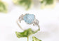 Raw Aquamarine and diamond twig ring on a leafy background, showcasing a unique nature-inspired design.