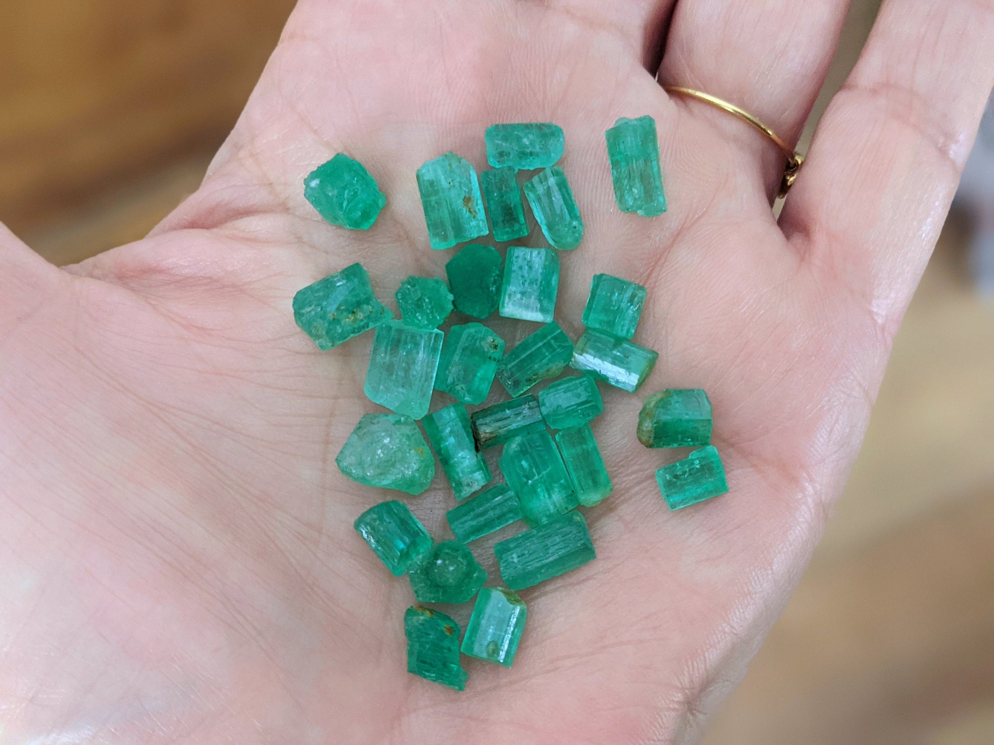 Raw green emerald stones from Swat Valley, Pakistan, displayed in a hand, showcasing their natural beauty and unique shapes.