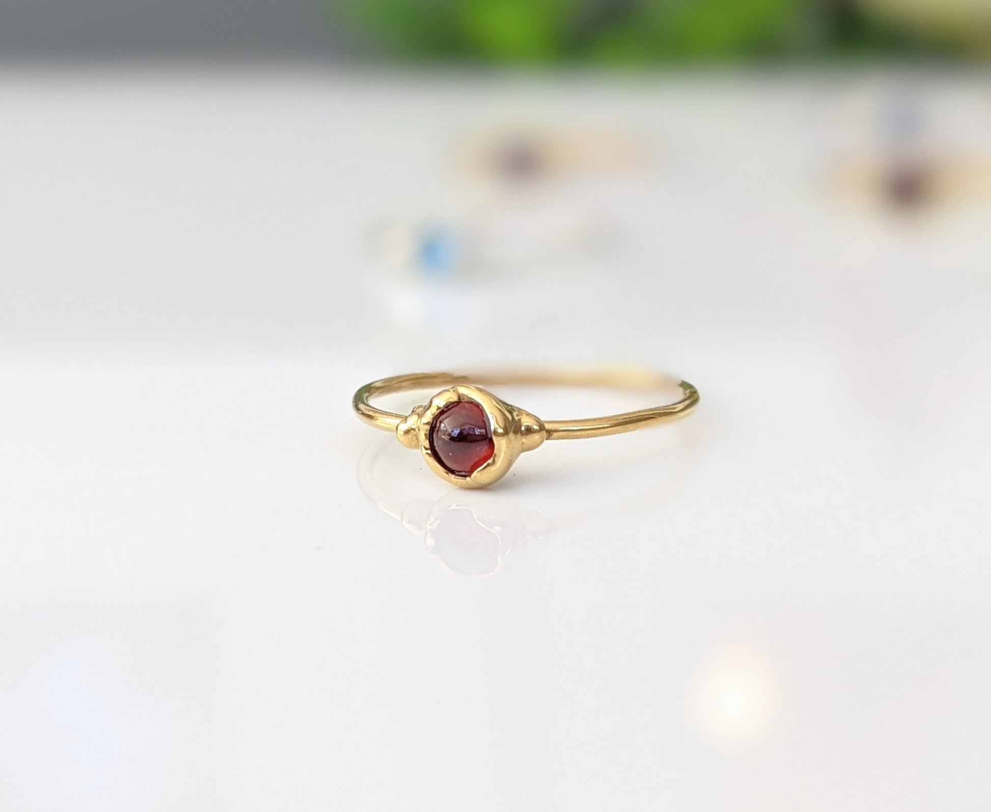 Dainty garnet stacking ring with a natural red garnet stone set on a 14k gold filled band.