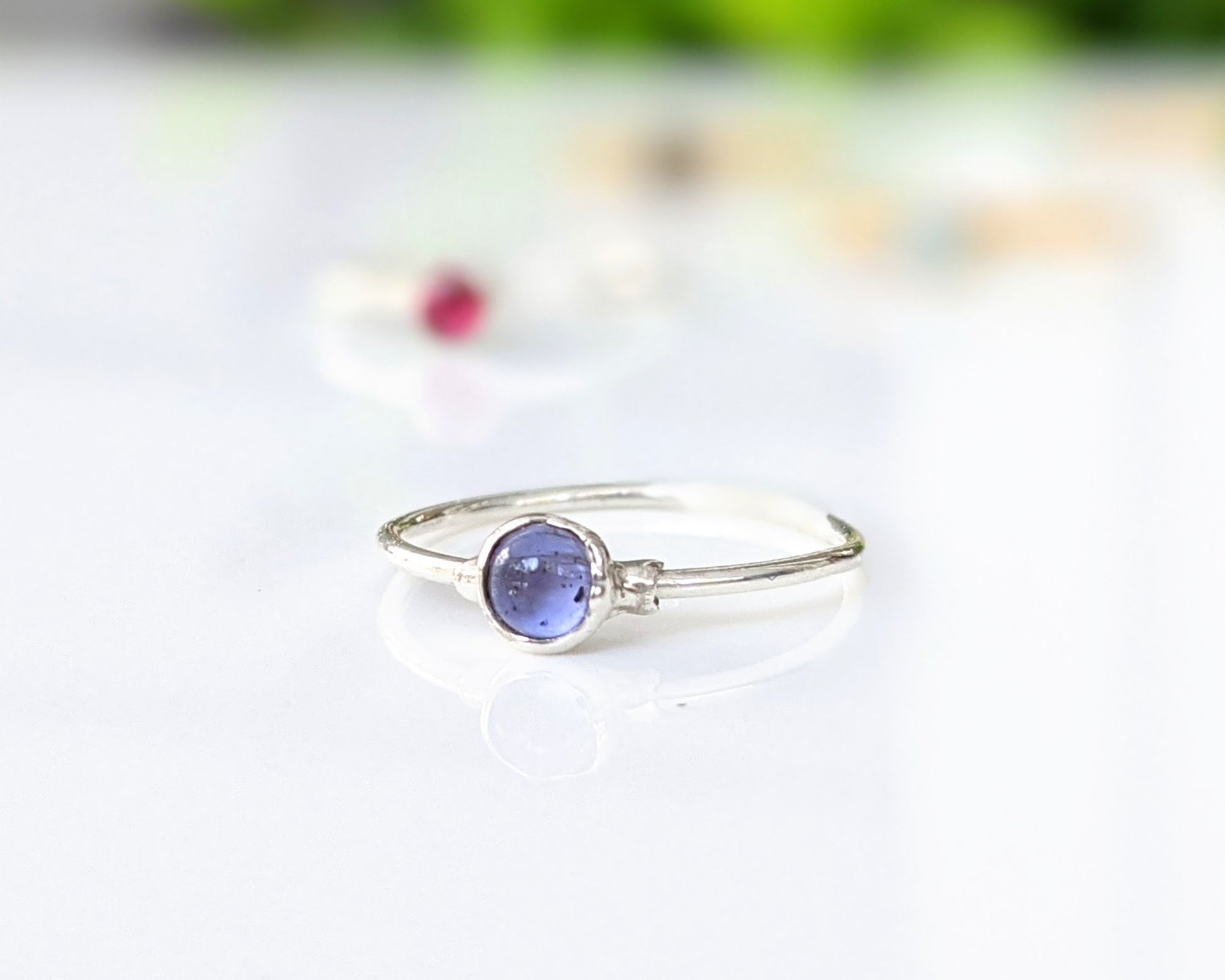 Dainty stacking ring featuring a 4mm natural purple-blue Tanzanite gemstone in a minimalist sterling silver band.