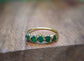 Raw Emerald Multi-stone Ring on a wooden background, showcasing 5-7 green Emeralds set in 14k Gold band.