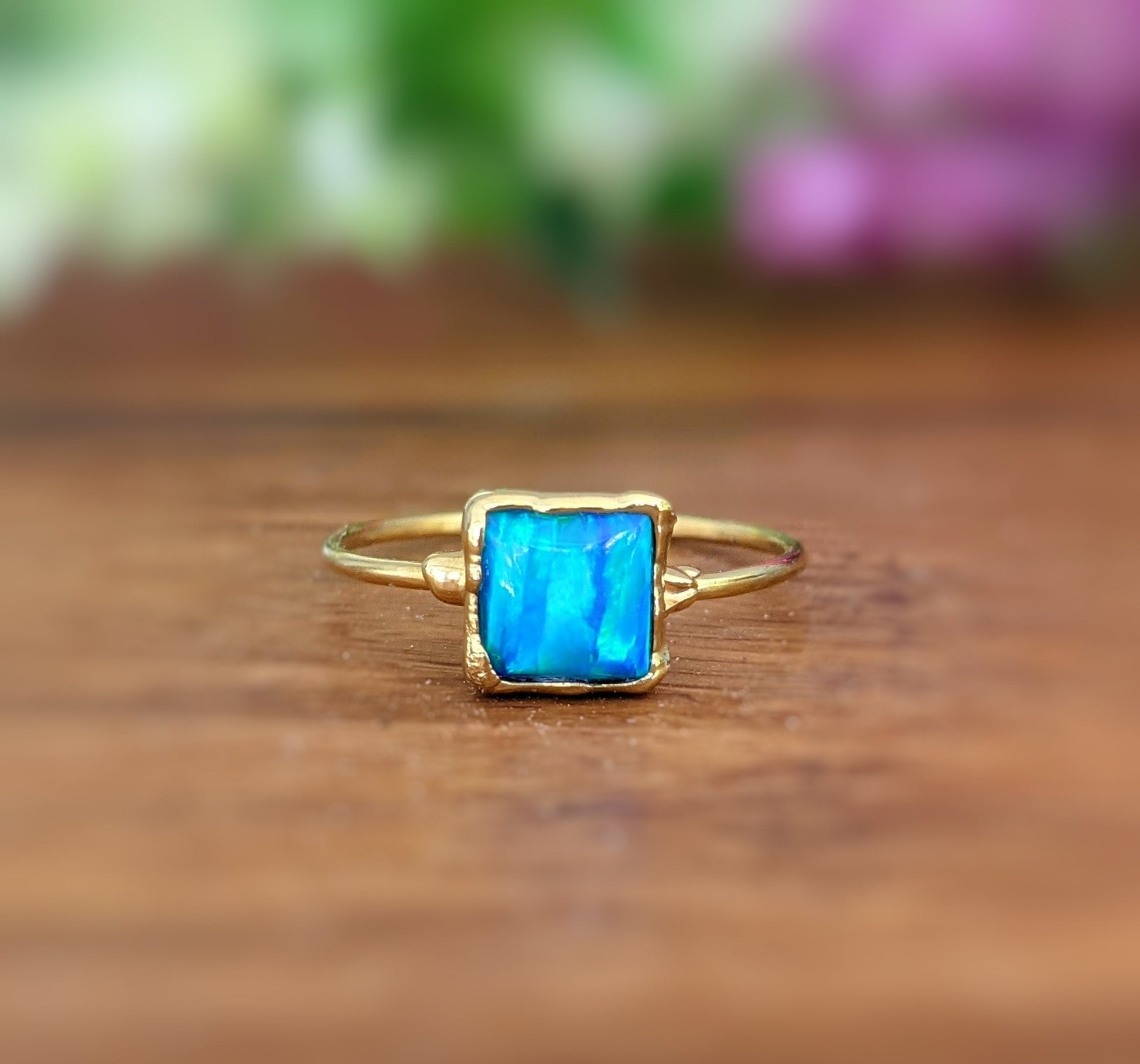 Aqua blue square cultured Opal ring in 18k gold plating on a delicate band, showcasing its unique vibrant hues.