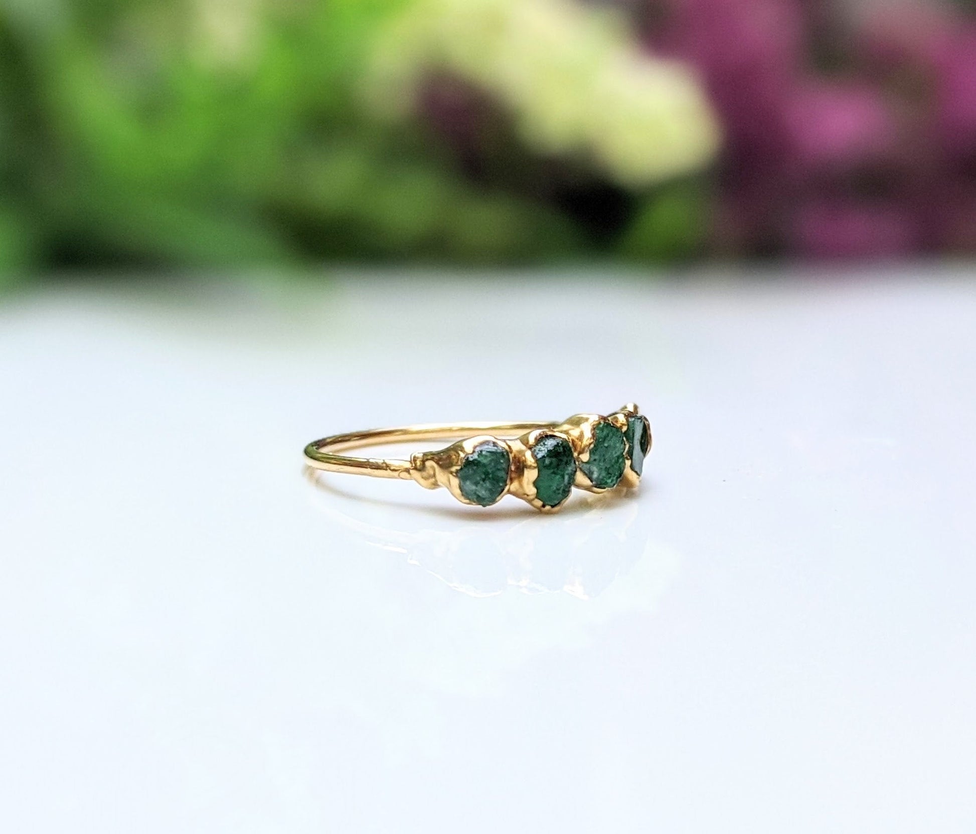 Raw Emerald multi-stone ring on a gold band, featuring 5-7 small raw emeralds, perfect May birthstone accessory.