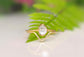 Gold Herkimer Diamond Chevron engagement ring set atop green fern leaves, symbolizing love and uniqueness.