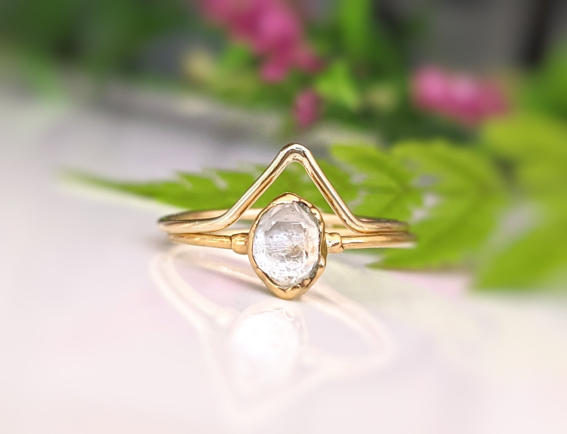 Herkimer diamond chevron engagement ring set on a blurred floral background, showcasing unique handcrafted design.