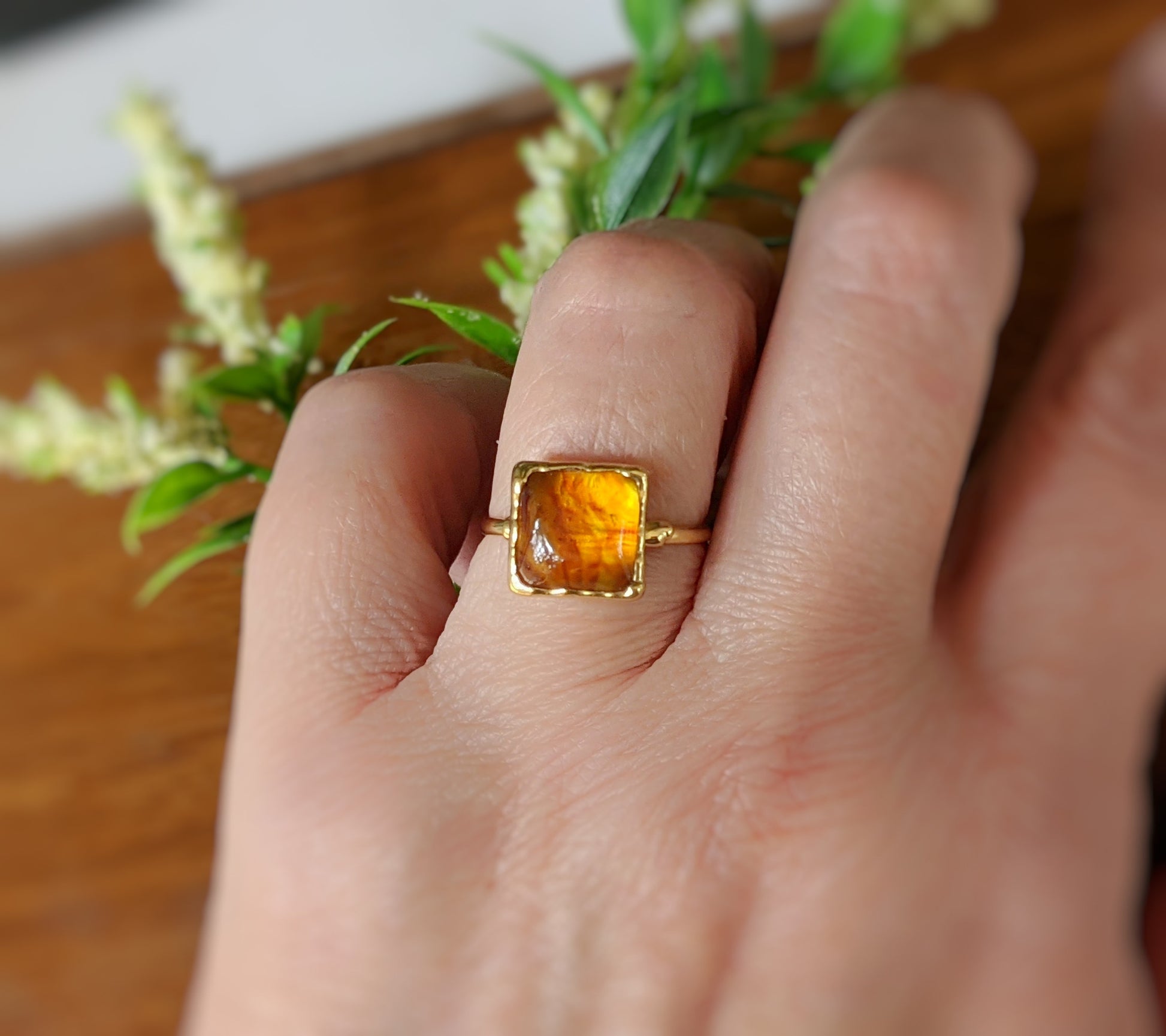 Honey color Baltic Amber square ring on a hand, set in 14k gold filled band, showcasing unique gemstone.